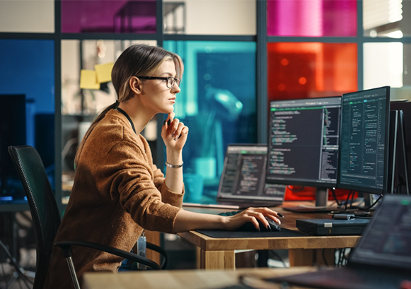 A woman working in front of multiple monitors