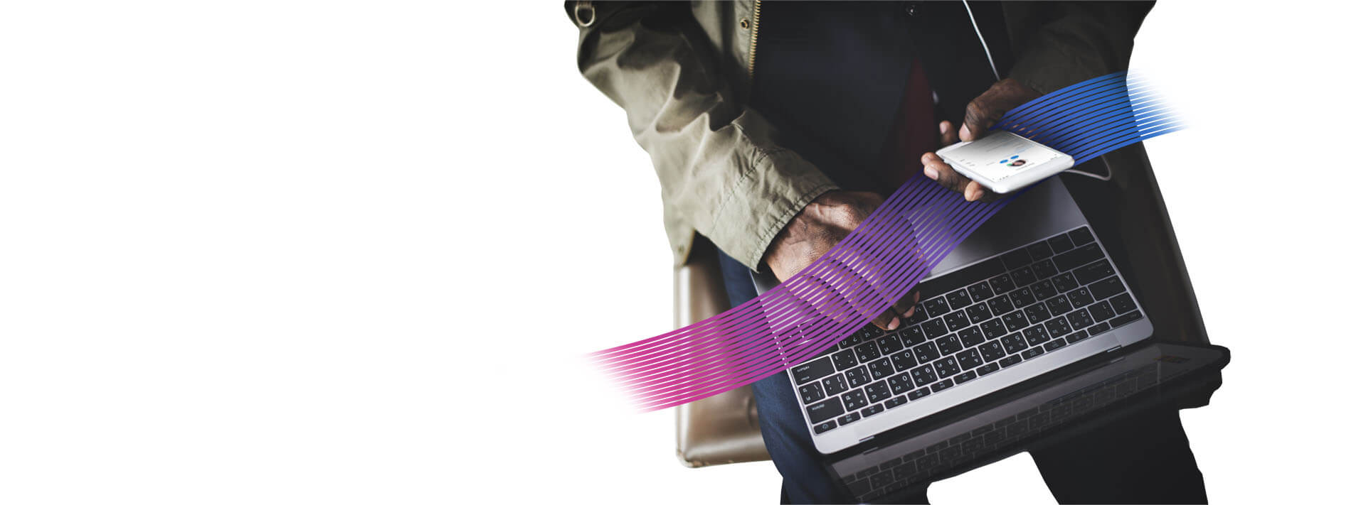 man working on a phone over a laptop