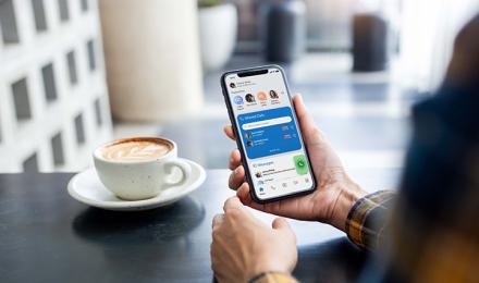 Someone looking at his phone and having a coffee