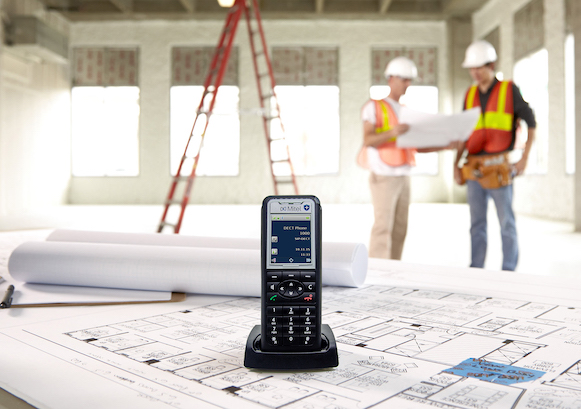 Deux personnes travaillant sur un chantier avec un telephone en premier plan