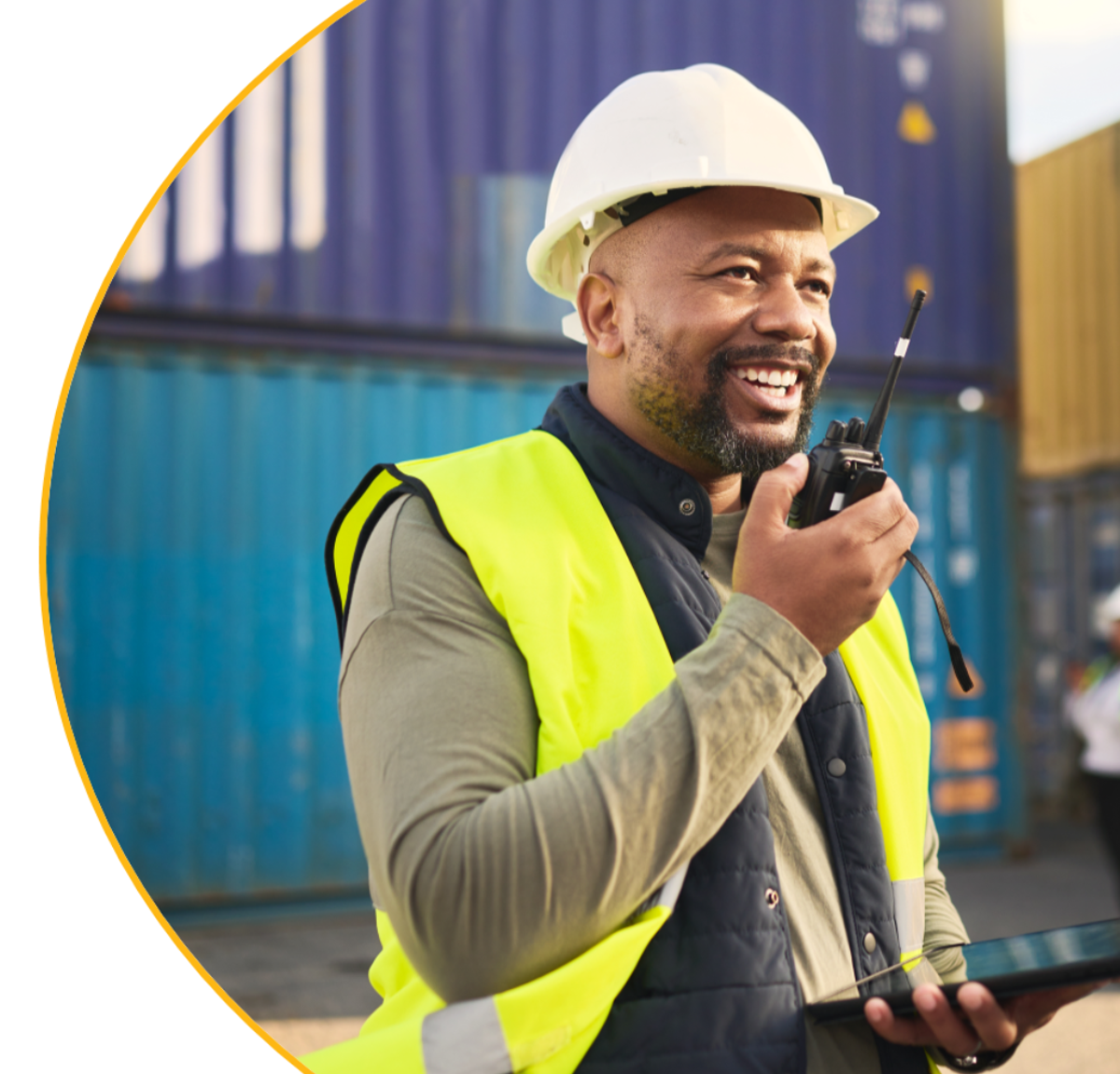 Homme dans un chantier parlant dans un talkie walkie et utilisant une tablette