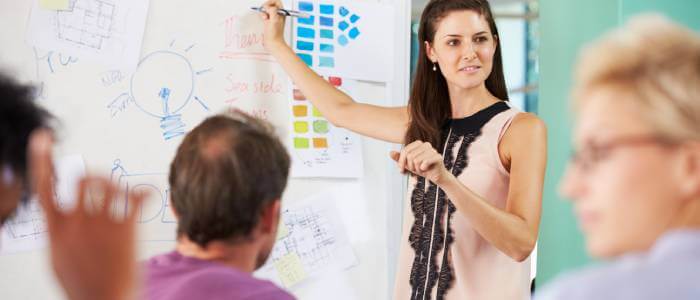 A woman showing post-it's on a whiteboard to other people