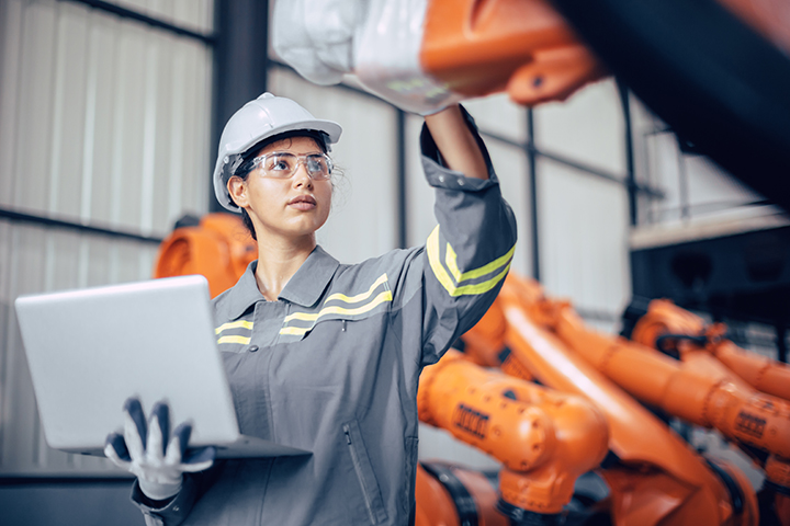 Manufacturing operative with laptop and safety wear